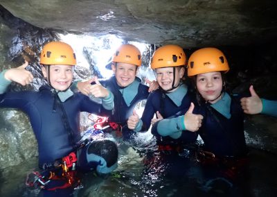 Groupe d'enfants réalisant une petite pause photo lors d'un passage ludique et facultatif sous un rocher dans le canyon de Eau Rousse en Savoie