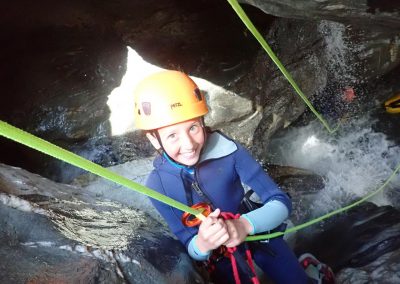 Enfant descendant une petite cascade en rappel lors d'un canyoning dès 8 ans